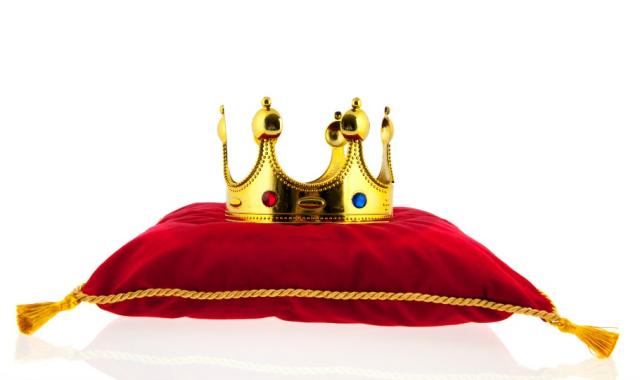Golden crown on red velvet pillow for coronation.