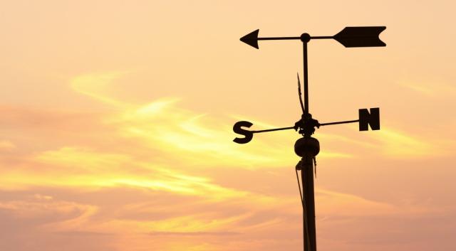 Silhouette of a weather vane over orange evening sky